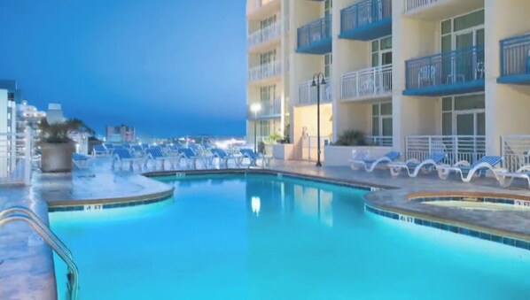 Relax by the pool surrounded by lounge chairs on a low, tiled deck.