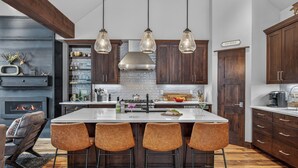 Una cocina moderna con una isla grande, armarios de madera oscura e iluminación colgante.