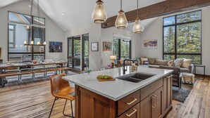 Una cocina amplia con una isla grande, armarios de madera e iluminación colgante.