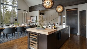 Una cocina moderna con isla central, armarios oscuros e iluminación colgante.