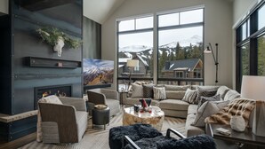 Una sala de estar moderna con chimenea, ventanas amplias y un rincón de descanso acogedor.