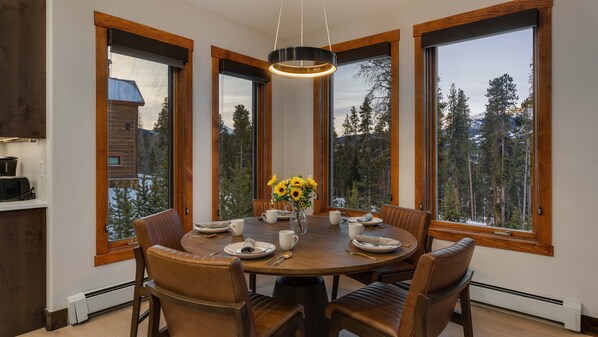 A dining area with a wooden table, leather chairs, and a vase of sunflowers. - Spacious w/Mountain Views + Hot Tub + Close to Skiing - Mountain Gate (Breckenridge)