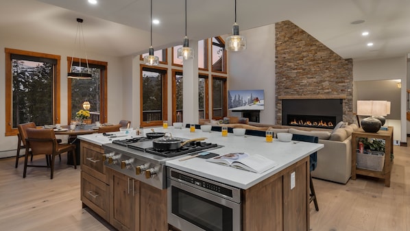 Une cuisine moderne dotée d’un grand îlot central, de meubles en bois et d’une cheminée en pierre.