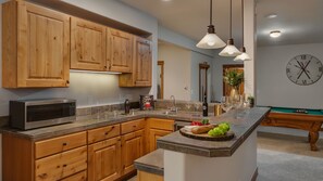A kitchen with wooden cabinets, a microwave, a sink, and a pool table. - Spacious w/Mountain Views + Hot Tub + Close to Skiing - Mountain Gate (Breckenridge)