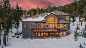 Ein großes, mehrstöckiges Haus mit Balkon, umgeben von Schnee und Bäumen.