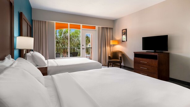 Une chambre d’hôtel avec deux lits, une télévision, un bureau et une chaise.