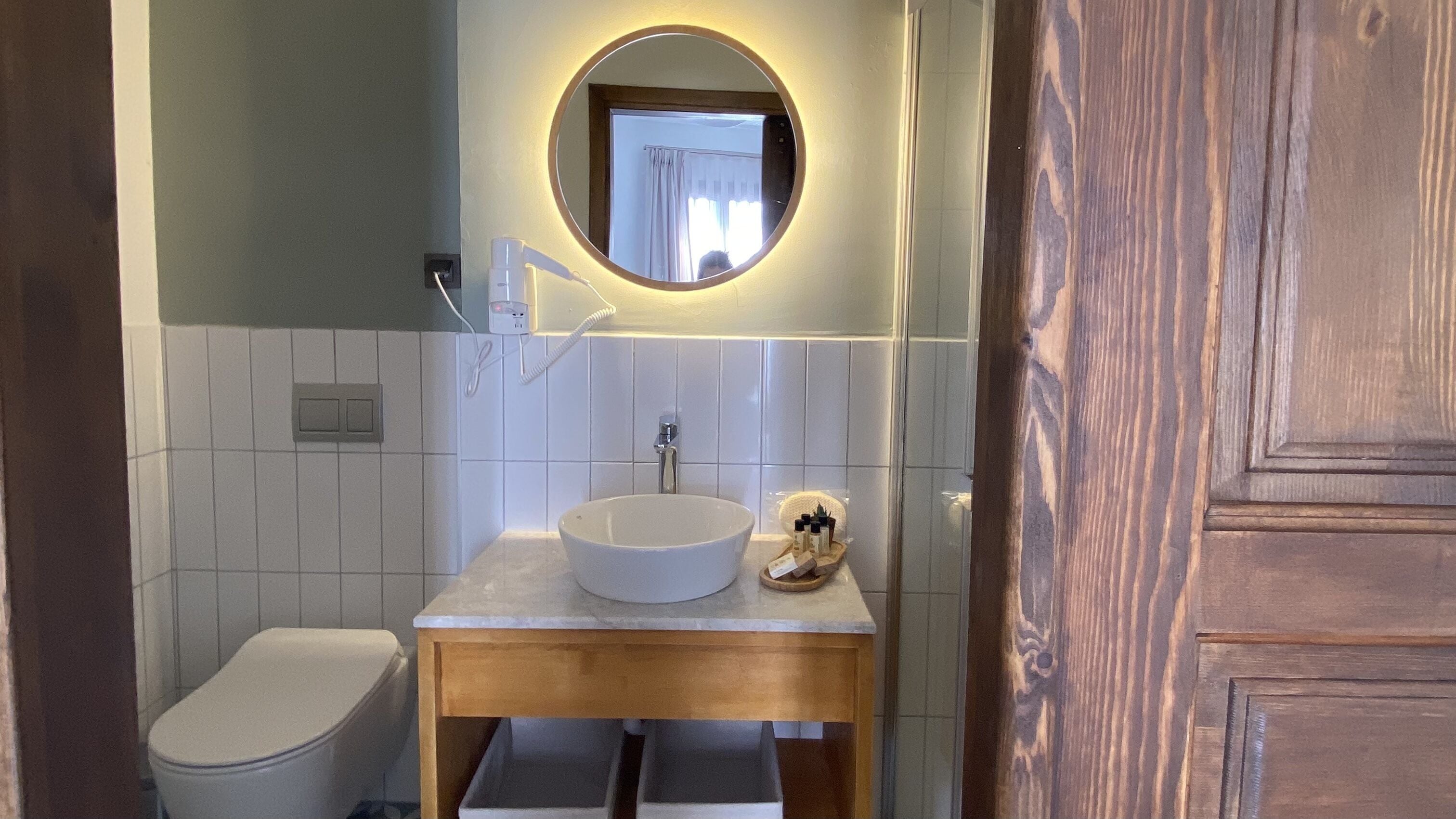 A bathroom with a white sink, a mirror, and a toilet.