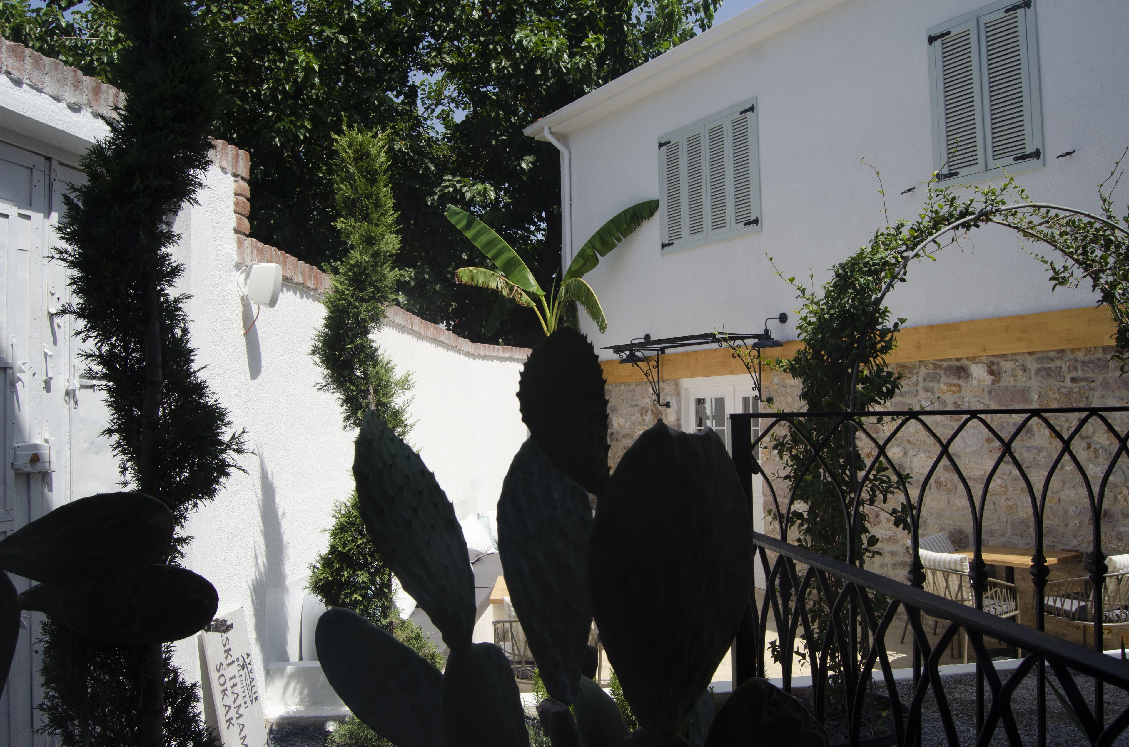 A courtyard with a white building, a stone wall, and a metal railing.