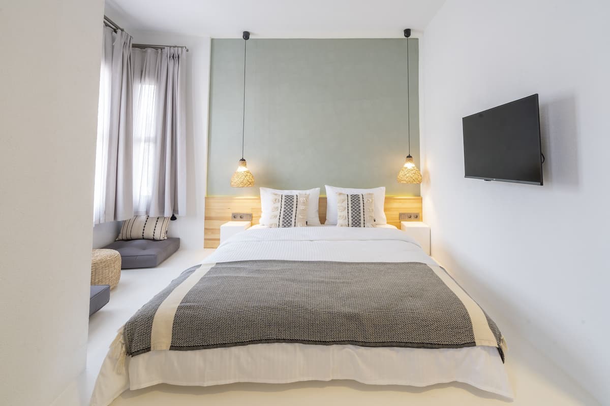 A modern bedroom with a bed, bedside lamps, a TV, and a window with curtains.