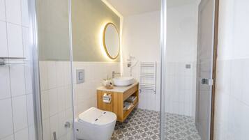 A modern bathroom with a glass shower enclosure, a wooden vanity with a sink, and patterned floor tiles.