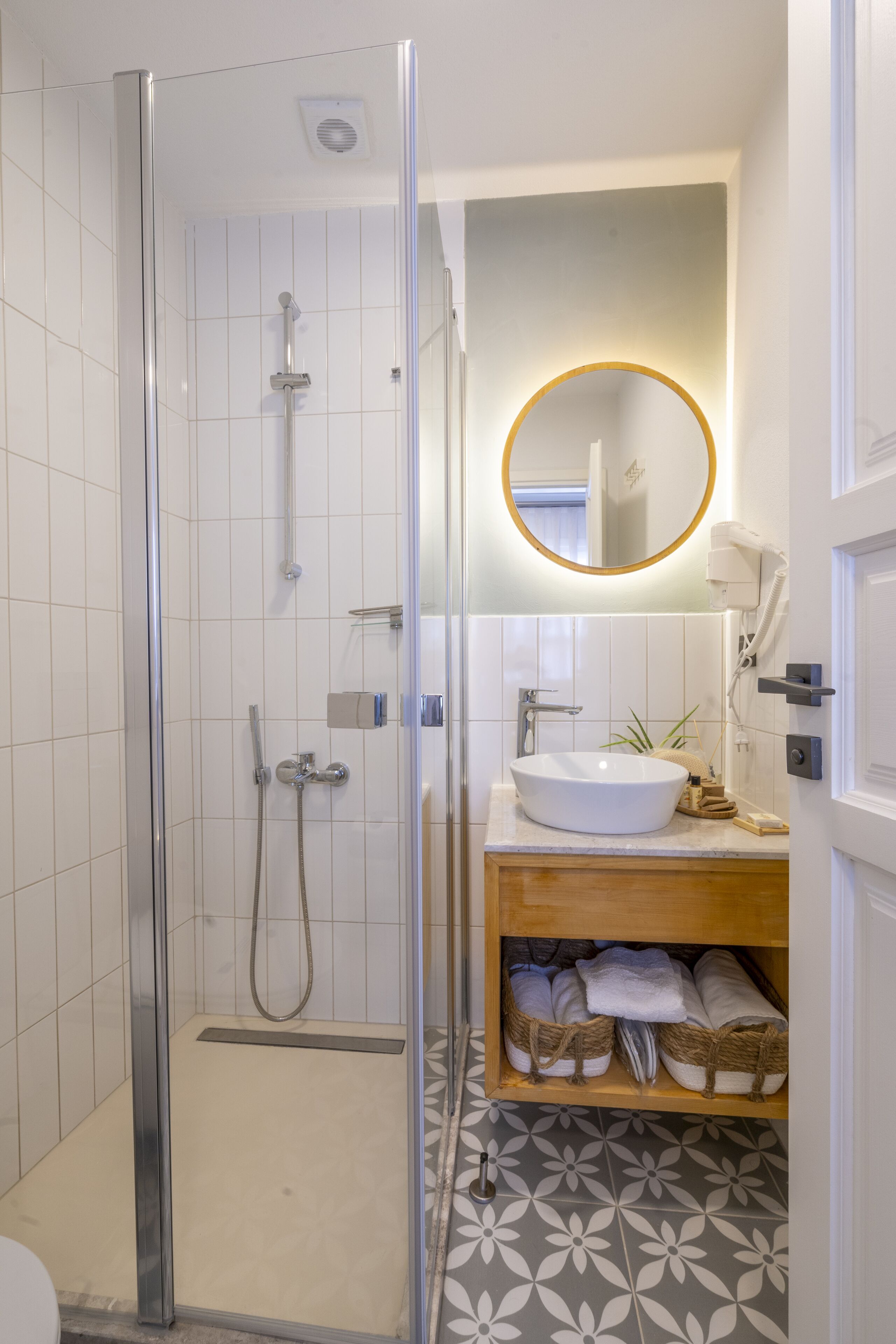 A modern bathroom with a glass-enclosed shower, a white sink, and a wooden vanity.
