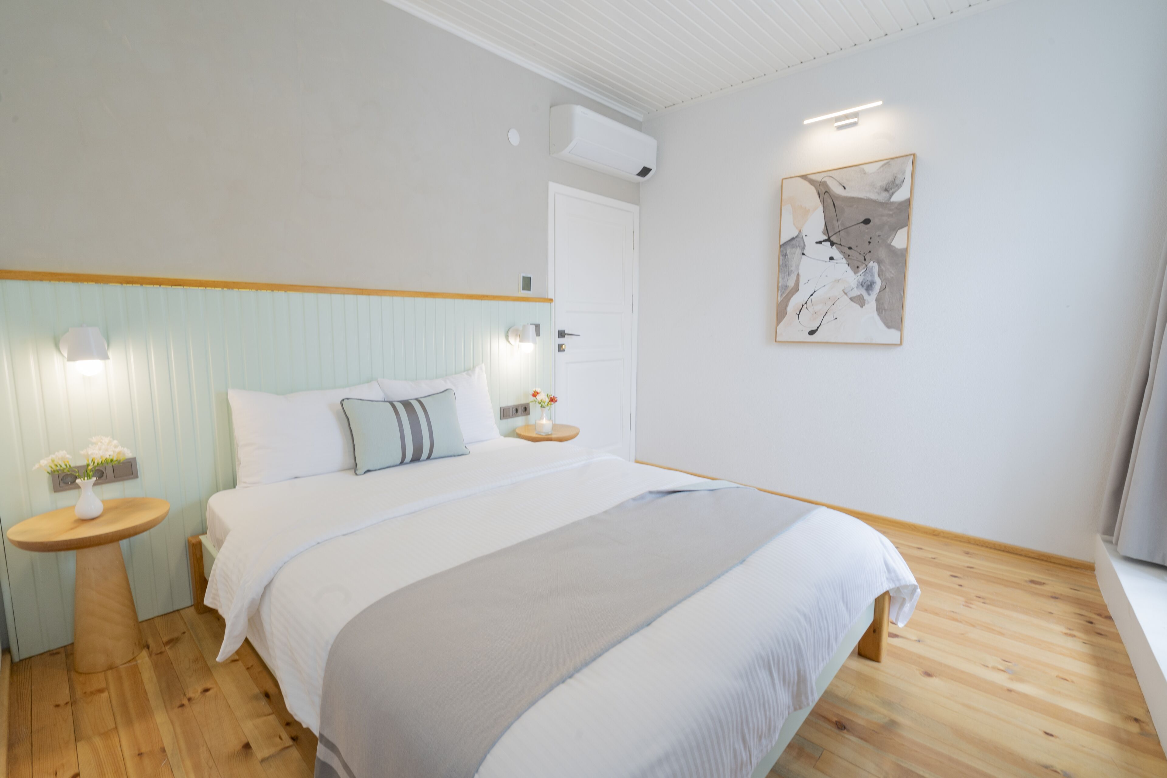 Un dormitorio moderno con una cama grande, suelo de madera y decoración minimalista.