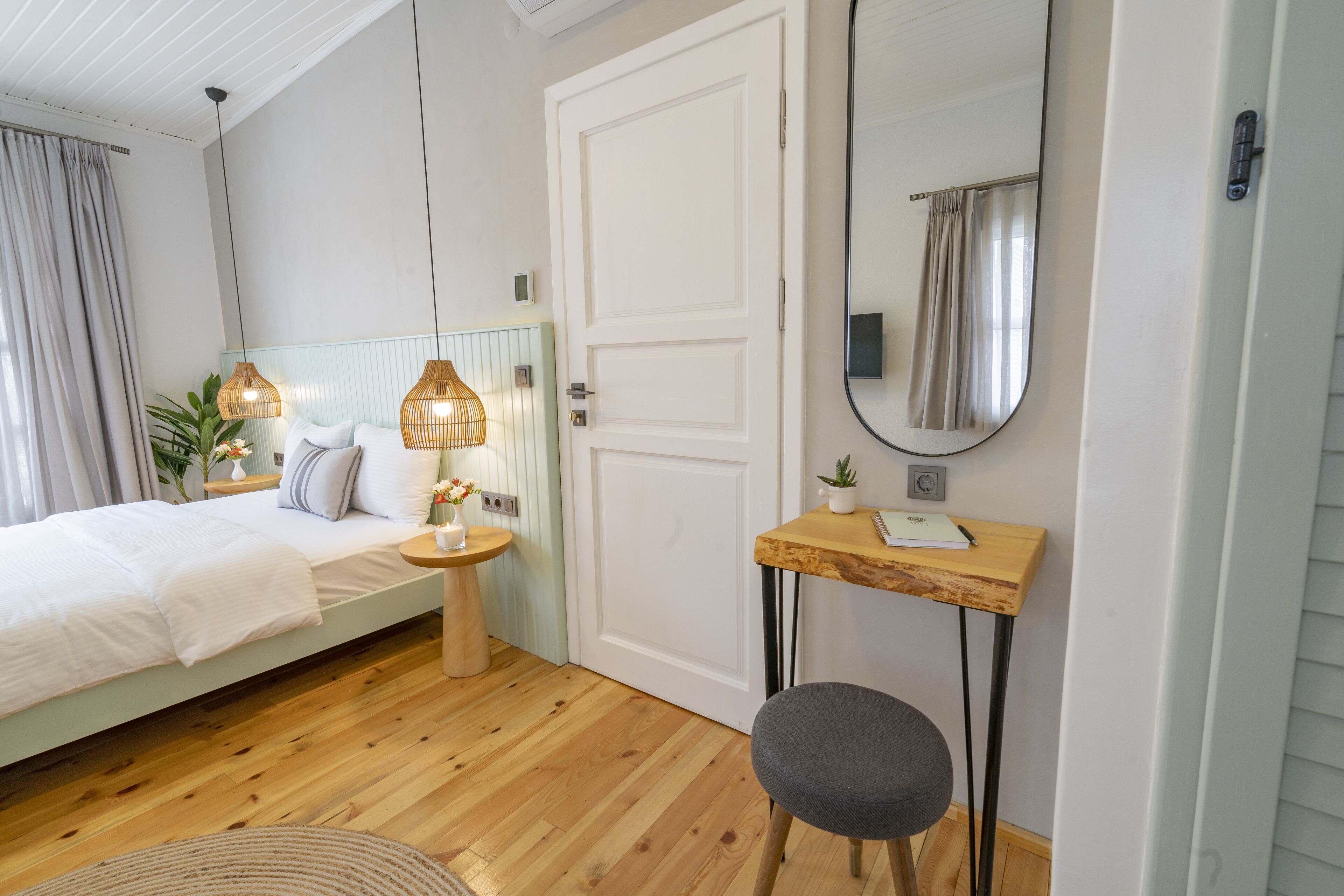 A bedroom with a bed, bedside table, lamp, chair, and a mirror.