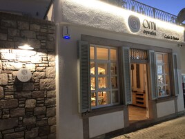 A building with a stone facade, a sign reading "OMI ayvalik," and a balcony with a railing.