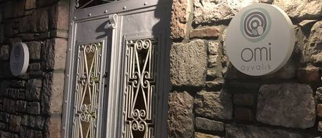 Un muro de piedra con una puerta de metal y un letrero circular con el texto "OMI".