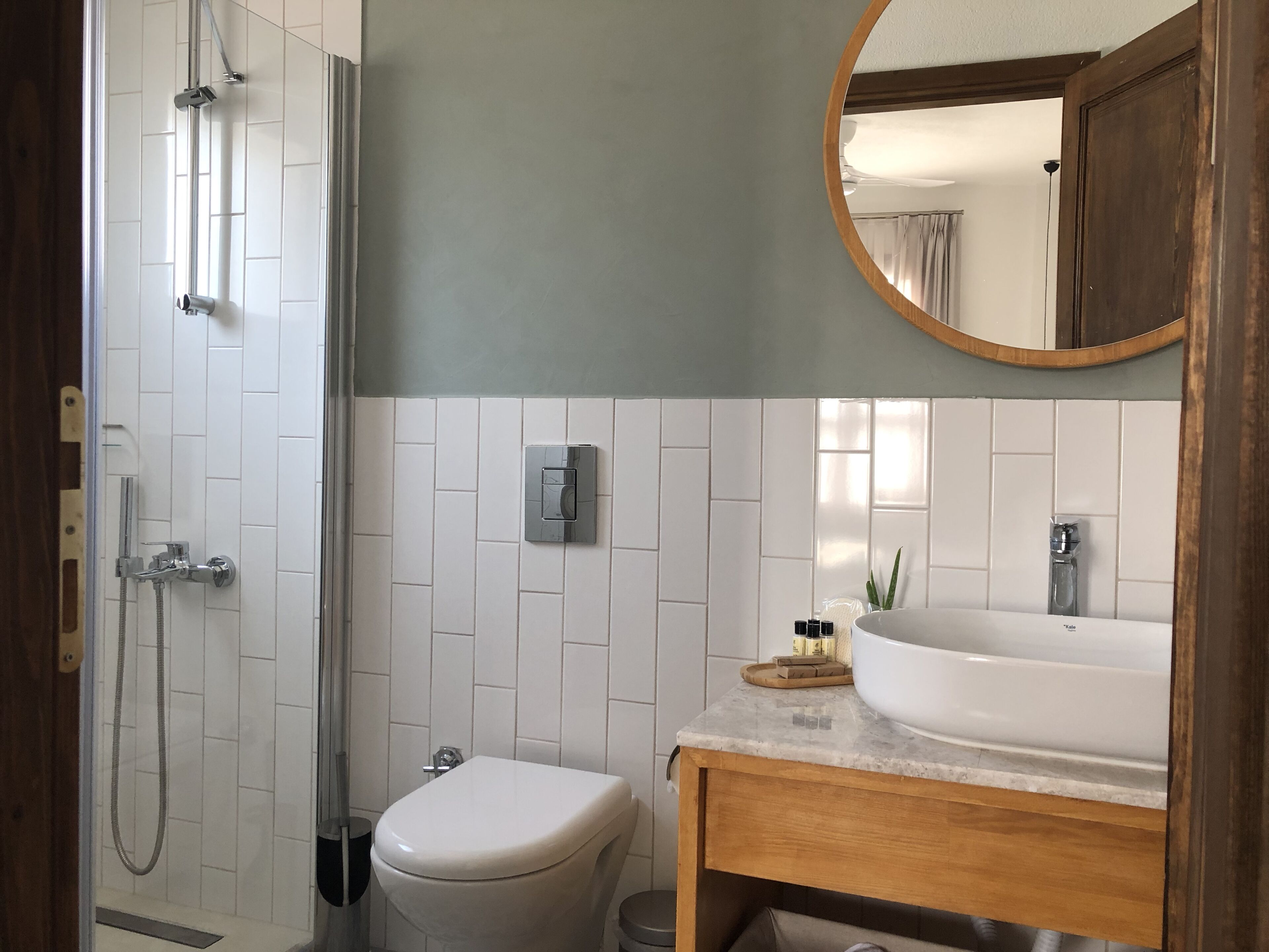 A bathroom with a shower, toilet, sink, and a mirror.