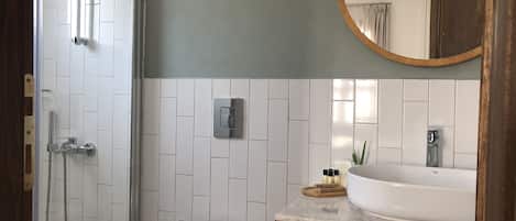A bathroom with a shower, toilet, sink, and a mirror.