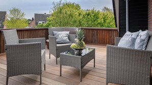 An outdoor patio with wicker furniture, a glass-top table, and a pineapple centerpiece. - Ben, Tinnum, Germany (Sylt-Ost)