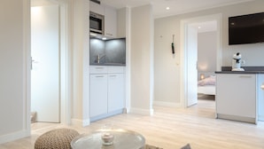 A modern kitchen with white cabinets, a built-in oven, and a microwave. There is a round table with a glass vase and a cushion. - Ben, Tinnum, Germany (Sylt-Ost)