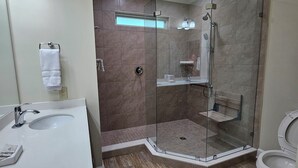 A modern bathroom with two sinks, a glass-enclosed shower, and a toilet.
