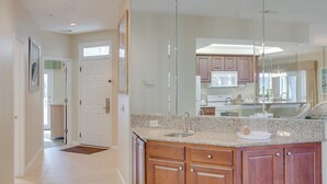 A modern kitchen with granite countertops, wooden cabinets, and a large mirror.