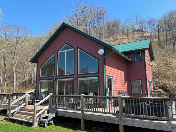 A red building with large windows and a green roof, connected to a wooden deck.