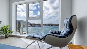 A modern room with a large window offering a view of a harbor and cityscape.