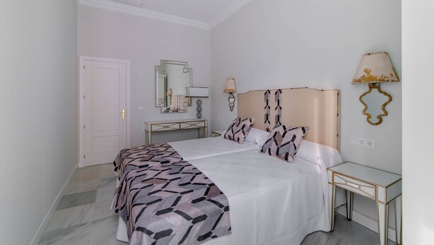 A bedroom with a bed, bedside tables, a mirror, and a lamp. - Apartamentos Abreu Suites (Seville)