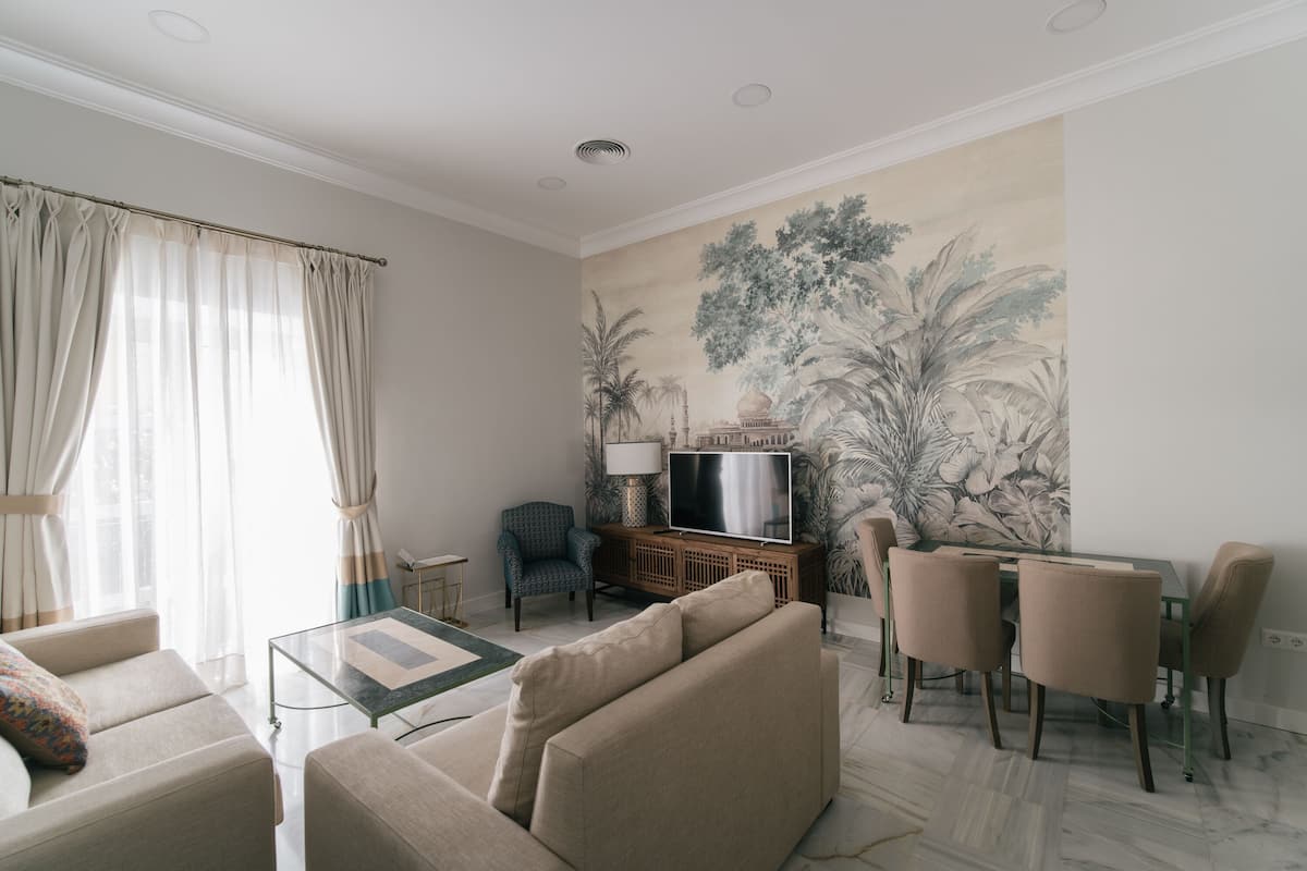 A living room with a sofa, a glass coffee table, a TV, and a dining area with chairs and a table.
