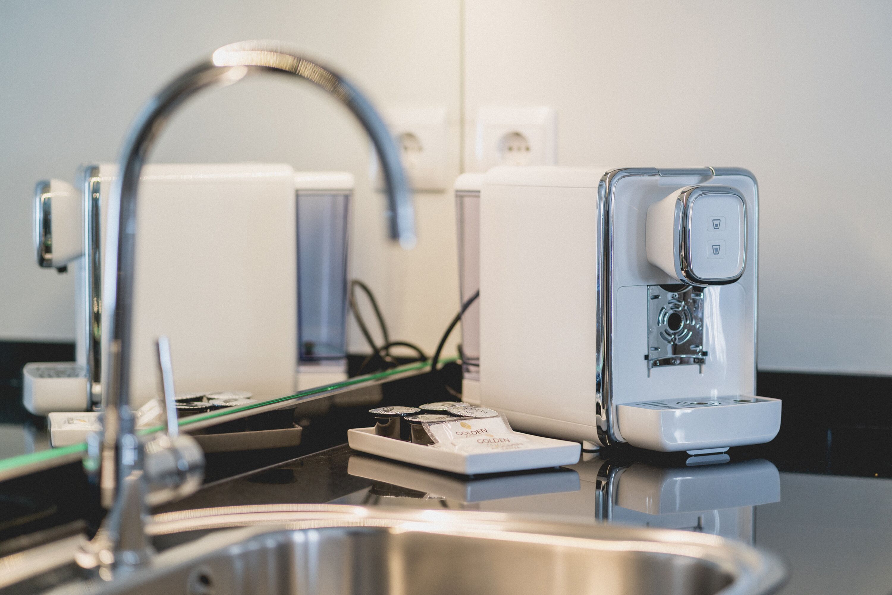 Una cocina moderna con un lavamanos de acero inoxidable, un grifo y una cafetera.