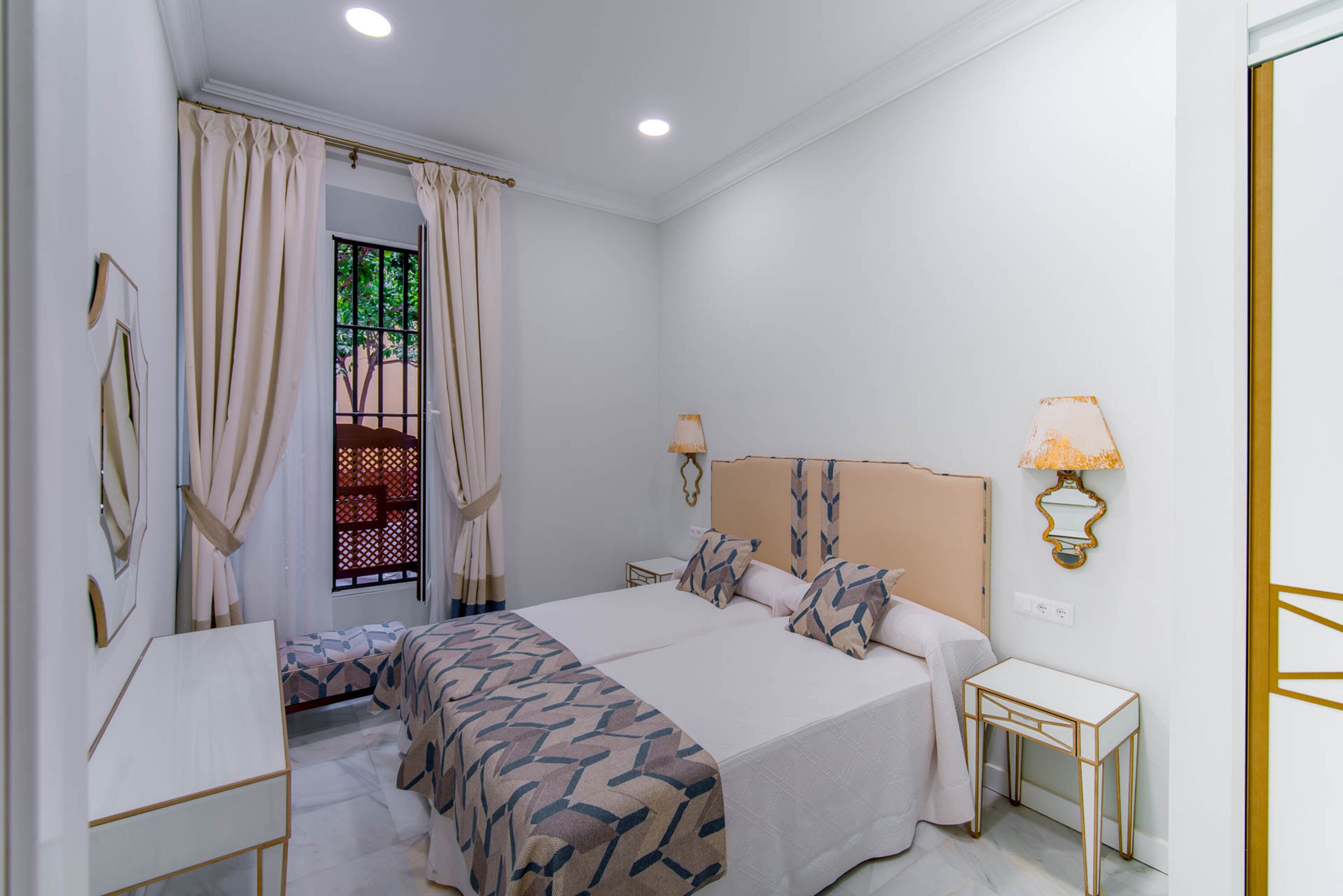 Un dormitorio con una cama grande, mesitas de noche y una ventana con cortinas.