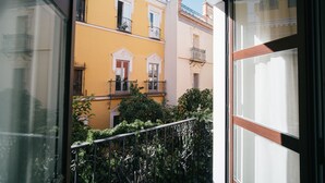 A view of a yellow building with balconies and a window with a wooden frame. - Apartamentos Abreu Suites (Seville)