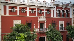 A red building with white trim, multiple windows, and a central entrance. - Apartamentos Abreu Suites (Seville)
