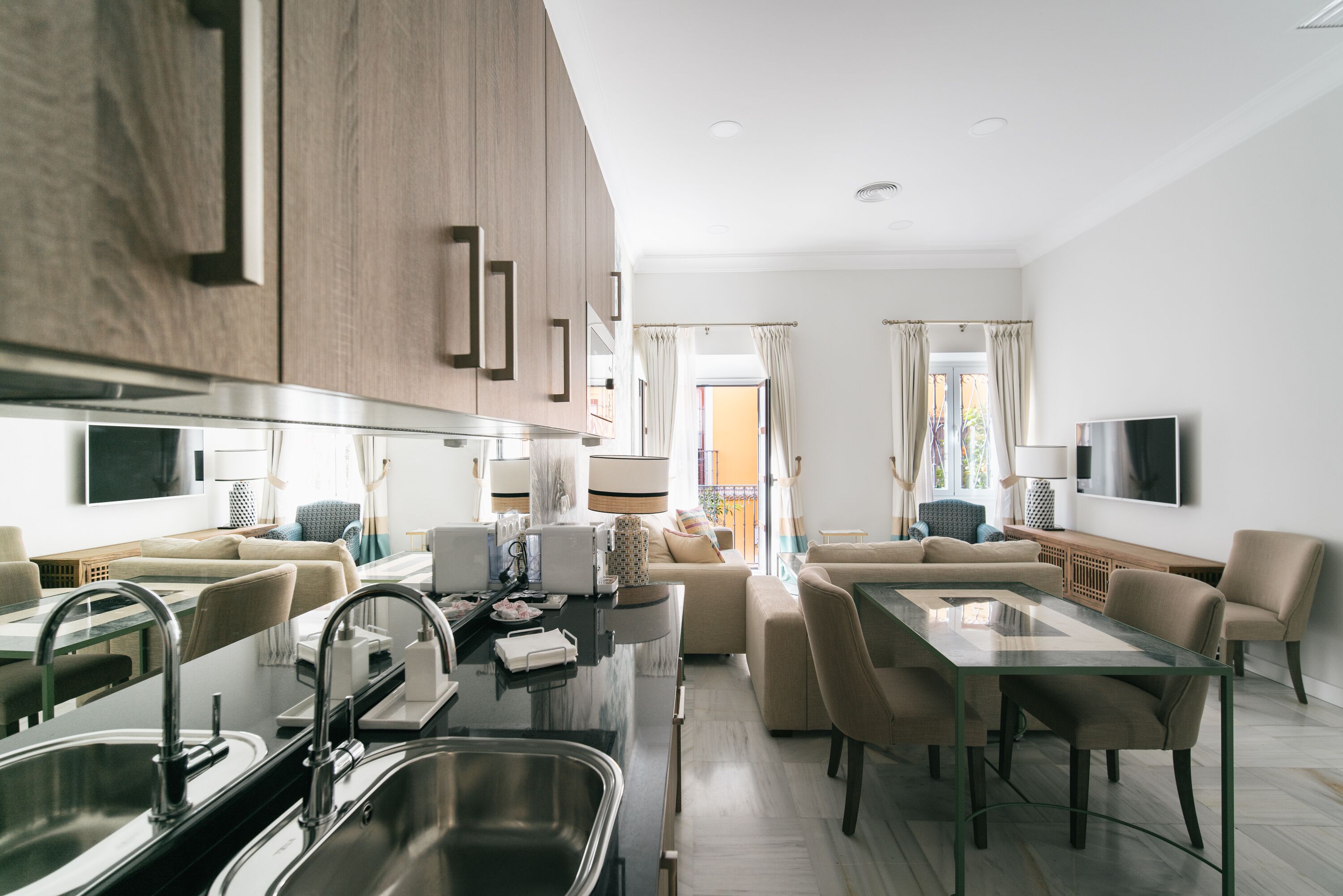 A modern kitchen with a dining area, featuring a glass-top table, built-in cabinets, and a large window.