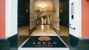 A hotel entrance with a black and white color scheme, a chandelier, and a black doormat with the hotel's name. - Apartamentos Abreu Suites (Seville)