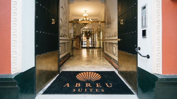 A hotel entrance with a black and white color scheme, a chandelier, and a black doormat with the hotel's name. - Apartamentos Abreu Suites (Seville)