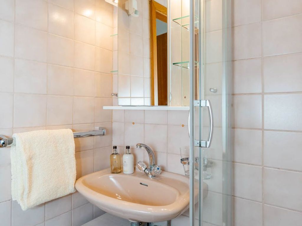 A bathroom with a sink, mirror, and glass shower enclosure.