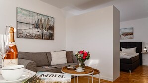 Un saló modern amb un sofà gris, una taula de centre amb un vas de flors, una ampolla de vi i una revista.