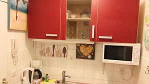 A compact kitchen with red cabinets, a microwave, a sink, and a coffee maker. - Koje16 - Very cozy, adorably small and yet perfectly equipped. (Sylt)