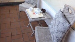 A small outdoor seating area with wicker chairs and a table, featuring a brick wall and a window with blinds. - Koje16 - Very cozy, adorably small and yet perfectly equipped. (Sylt)