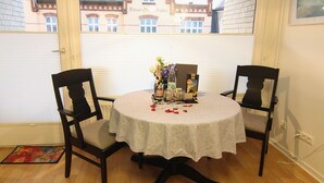 A round table with a lace tablecloth, two chairs, and a small table centerpiece with flowers and a bottle. - Koje16 - Very cozy, adorably small and yet perfectly equipped. (Sylt)