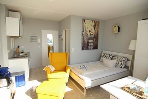 Een compacte hotelkamer met een bed, een klein bureau, een stoel en een kitchenette.