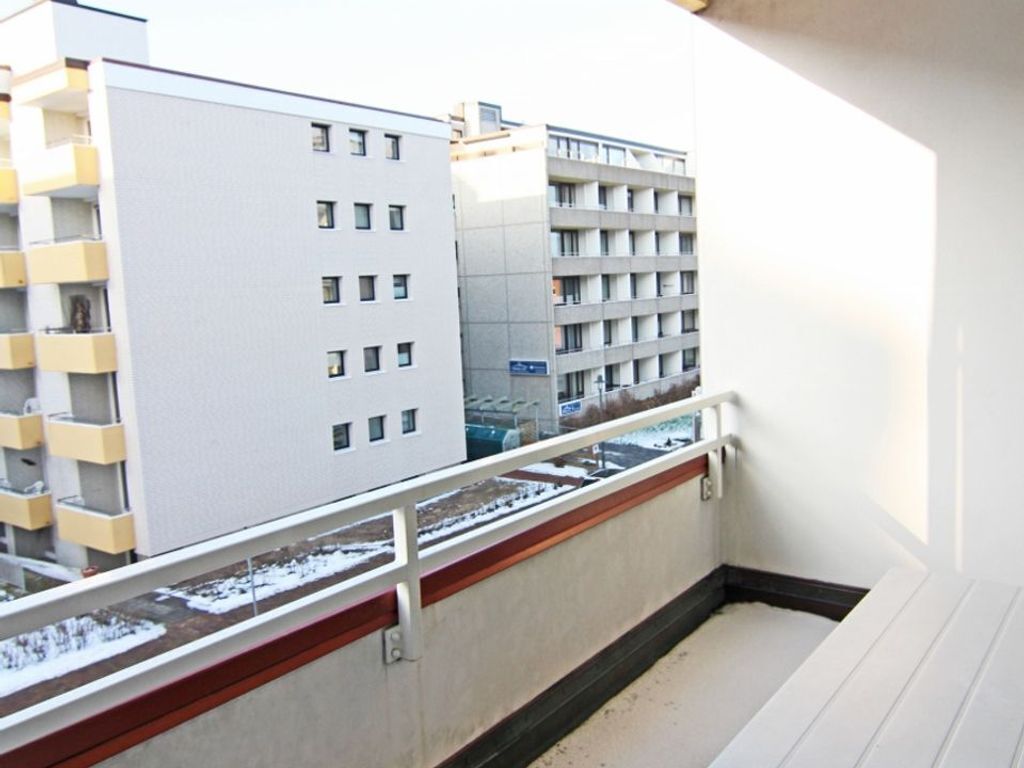 Ein Balkon mit Blick auf benachbarte Gebäude, einem Geländer und verschneitem Boden.
