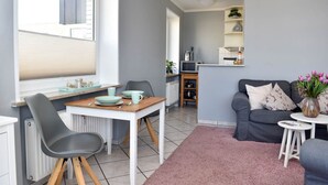 Un espacio habitable compacto con zona de comedor, sofá y pequeña cocina.