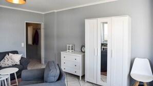 Una sala moderna con un sofá gris, un aparador blanco y un armario.