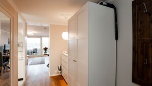 Un couloir avec un plancher en bois, une armoire blanche, une petite table blanche et un meuble en bois.