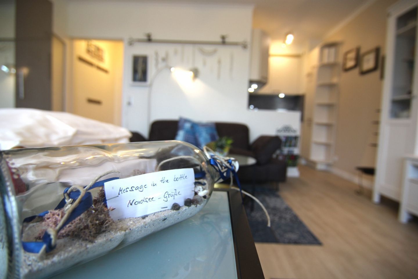 A room with a glass bottle containing a message, a sofa, a coffee table, and a bookshelf.