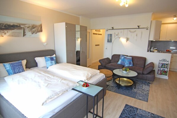 Une chambre d’hôtel moderne équipée d’un lit, d’un canapé, d’une petite table et d ’une kitchenette.
