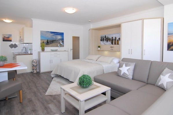 A modern, well-lit apartment with a bed, sofa, and dining area.