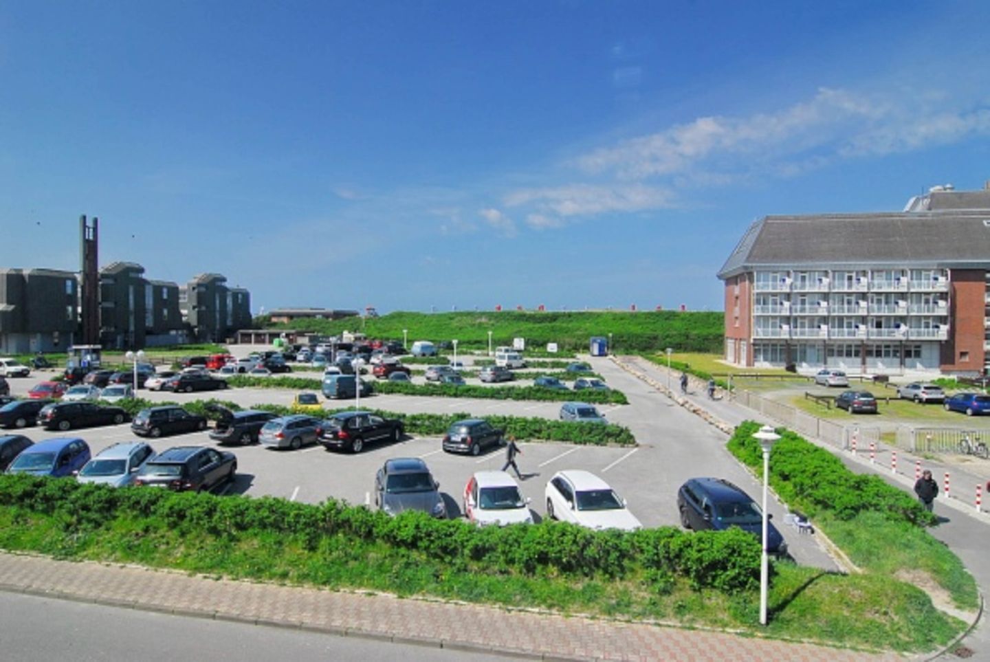 A parking lot with multiple cars and a building with a red brick facade.